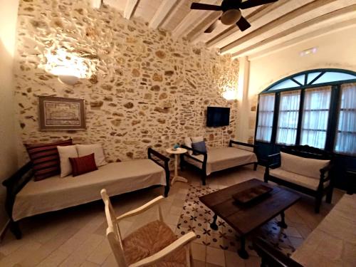 a living room with couches and chairs and a stone wall at Villa Aposperitis in Panormos Rethymno