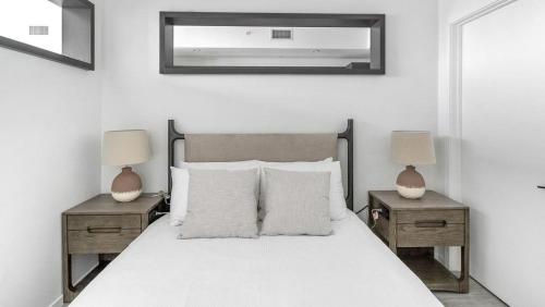 een witte slaapkamer met een bed met 2 nachtkastjes en 2 lampen bij Landing Modern Apartment with Amazing Amenities (ID1398X783) in Fort Lauderdale