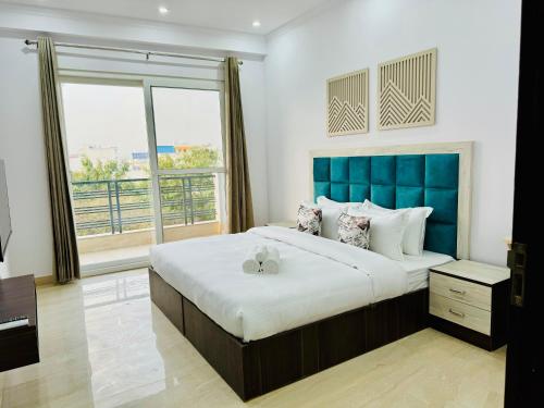 a bedroom with a large bed with a blue headboard at ZEN Suites - Golf Course Road Gurgaon in Gurgaon