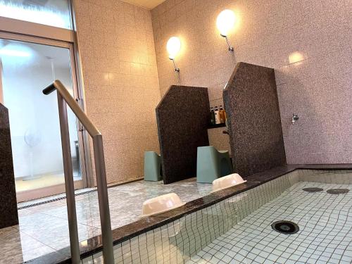 a bathroom with a swimming pool with two toilets at APA Hotel Mie Kameyama in Kameyama