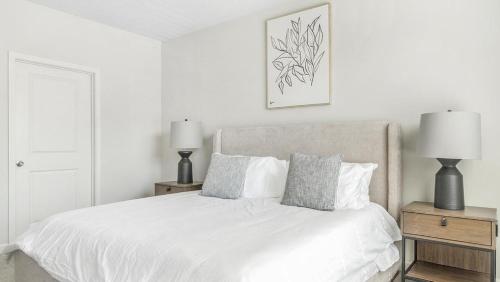 ein weißes Schlafzimmer mit einem weißen Bett mit zwei Lampen in der Unterkunft Landing Modern Apartment with Amazing Amenities (ID1002X885) in Wake Forest