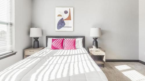 ein weißes Schlafzimmer mit einem Bett mit rosa Kissen in der Unterkunft Landing Modern Apartment with Amazing Amenities (ID3676X65) in Perrysburg