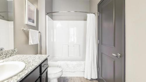 ein weißes Bad mit einem WC und einer Dusche in der Unterkunft Landing Modern Apartment with Amazing Amenities (ID3676X65) in Perrysburg