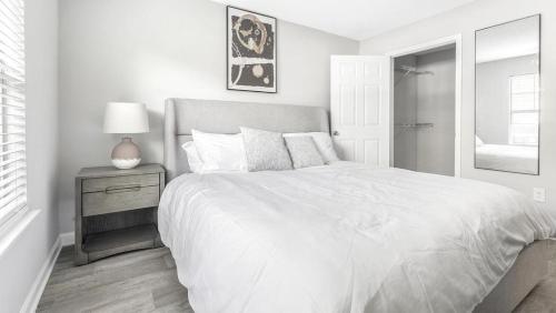 um quarto branco com uma cama grande e uma mesa de cabeceira em Landing Modern Apartment with Amazing Amenities (ID9155X81) em Durham