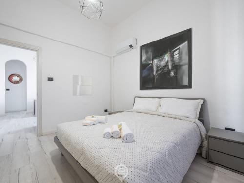 a white bedroom with a bed with towels on it at Port View Apartment in Cagliari