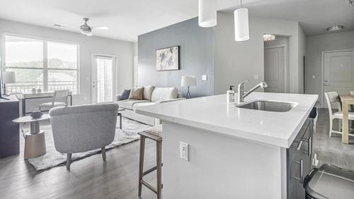 uma cozinha com um lavatório e uma sala de estar em Landing Modern Apartment with Amazing Amenities (ID1210X718) em Wake Forest