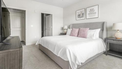 um quarto branco com uma cama e uma televisão em Landing Modern Apartment with Amazing Amenities (ID1210X718) em Wake Forest