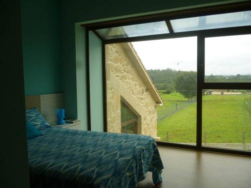 1 dormitorio con cama y ventana grande en 4 bedrooms house with private pool jacuzzi and wifi at Roxos, en Santiago de Compostela