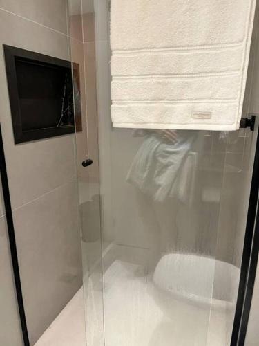 a shower with a glass door and a towel at Lindo estúdio em Marilia - ao lado do Ibis in Marília