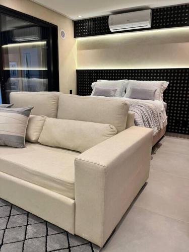 Sofá blanco en una habitación con 2 camas en Lindo estúdio em Marilia - ao lado do Ibis, en Marília