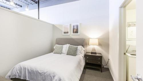 Dormitorio blanco con cama y lámpara en Landing Modern Apartment with Amazing Amenities (ID9106X83) en Omaha