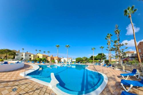 a swimming pool at a resort with chairs and palm trees at 2 bedrooms appartement with shared pool terrace and wifi at Costa Adeje in Santa Cruz de Tenerife