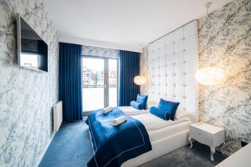 a bedroom with a bed with blue pillows at Apartament Amber Centrum z basenem in Gdańsk