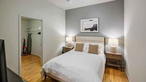 una camera con un letto bianco e due comodini con lampade di Landing Modern Apartment with Amazing Amenities (ID8369X10) a Omaha
