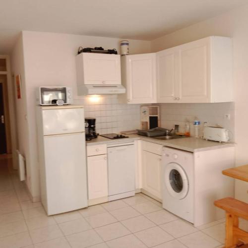 une cuisine avec des armoires blanches et une machine à laver dans l'établissement Studio cabine équipée pour 4 personnes 4CALYI/2, à Canet