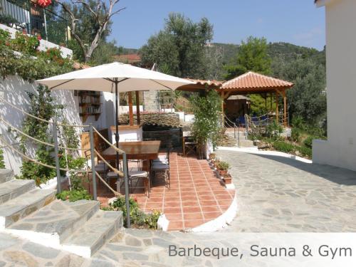 um pátio com um guarda-sol, uma mesa e cadeiras em Eye Q Resort em Skiathos