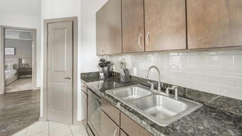 a kitchen with a sink and wooden cabinets at Landing Modern Apartment with Amazing Amenities (ID1992) in Houston