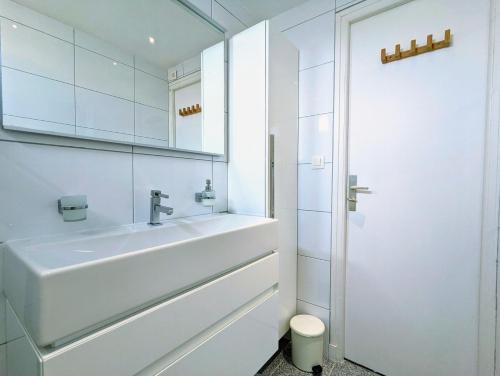 La salle de bains blanche est pourvue d'un lavabo et d'un miroir. dans l'établissement Appartement T4/parking privé/wifi/50m de la plage, au Cap d'Agde
