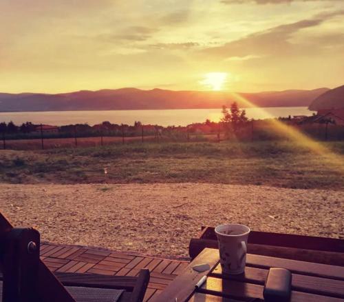 a coffee cup sitting on a table with the sunset at Od svitanja do sumraka in Golubac