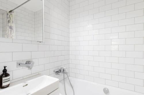 a white bathroom with a sink and a bath tub at Central London Stylish Room in London