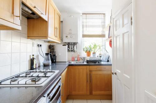 a kitchen with wooden cabinets and a stove top oven at Central London Stylish Room in London