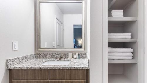 uma casa de banho com lavatório, espelho e toalhas em Landing Modern Apartment with Amazing Amenities (ID9245X93) em Irving