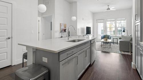 a white kitchen with a sink and a living room at Landing Modern Apartment with Amazing Amenities (ID1384X699) in Orlando