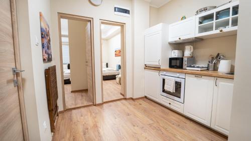 a kitchen with white cabinets and a door leading to a bedroom at Palmy Home Dunakeszi in Dunakeszi
