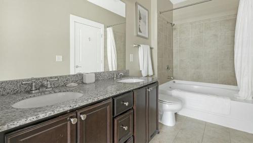 y baño con 2 lavabos, bañera y aseo. en Landing Modern Apartment with Amazing Amenities (ID2268X42), en Raleigh