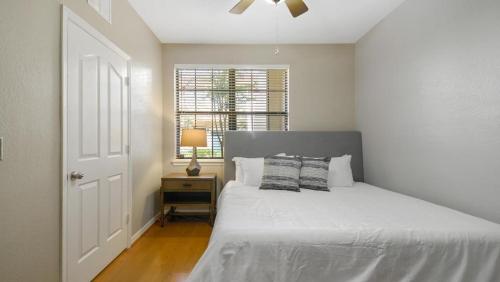 a white bedroom with a bed and a window at Landing Modern Apartment with Amazing Amenities (ID4287X35) in Orlando