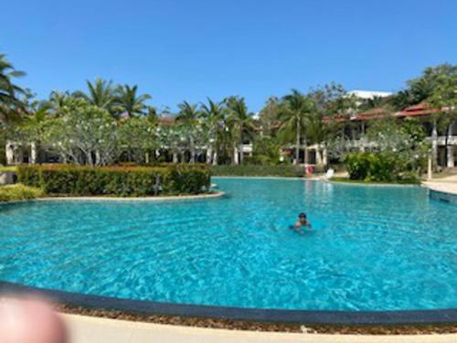 a person swimming in a large swimming pool at 2Bed Villa - Sleeps 4 - Poolside Wifi Near Beach in Layan Beach