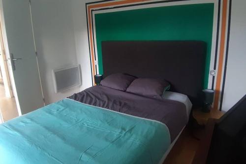 Ce lit se trouve dans une chambre dotée d'un mur vert. dans l'établissement Maison d'une chambre avec piscine partagee terrasse et wifi a Sainte Terre, à Sainte-Terre