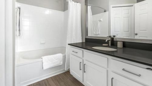 a white bathroom with a sink and a tub at Landing Modern Apartment with Amazing Amenities (ID1375X099) in Charlotte