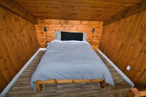 a bed in a wooden room in a cabin at CHALET AUX MÉLÈZES AVEC SPA ET PISCINE CREUSÉ PRIVÉ in Beauceville