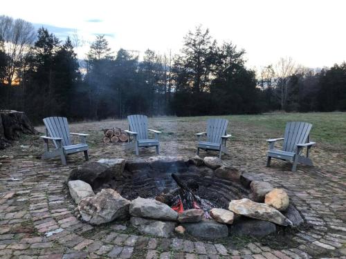 Lewisville的住宿－Cozy and Peaceful Tiny House on a 100-acre Farm，院子里一个火坑周围坐着三把椅子