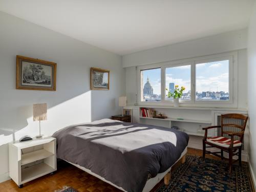 une chambre avec un lit, une chaise et une fenêtre dans l'établissement Eiffel Tower Loft residence, à Paris