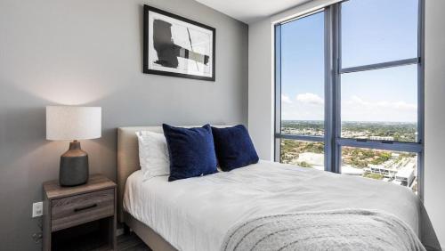 Landing Modern Apartment with Amazing Amenities (ID870) في فورت لاودردال: غرفة نوم مع سرير ووسائد زرقاء ونافذة