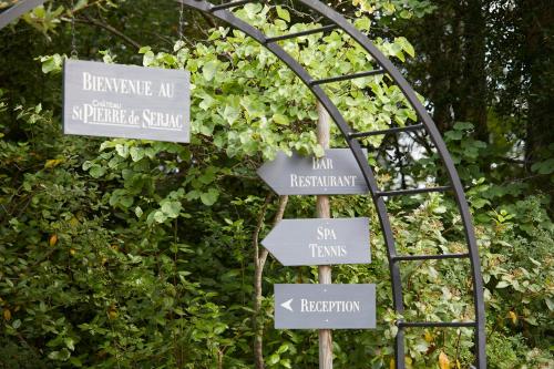 un letrero de la calle con letreros delante de un arbusto en Château St Pierre de Serjac en Puissalicon