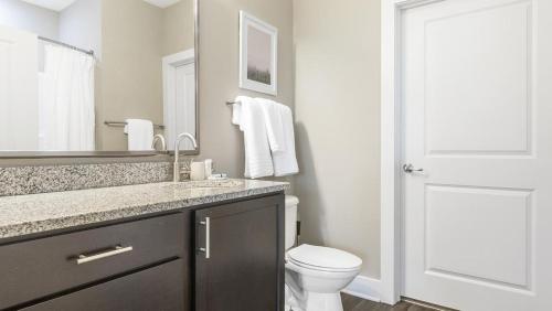 La salle de bains est pourvue de toilettes, d'un lavabo et d'un miroir. dans l'établissement Landing Modern Apartment with Amazing Amenities (ID9577X84), à Charlotte