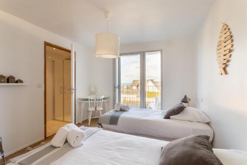 two beds in a room with a window at Ty Far - Villa pour 8 vue sur le Port in Erquy