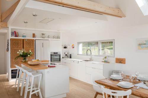 a kitchen with white cabinets and a wooden table at Ty Far - Villa pour 8 vue sur le Port in Erquy
