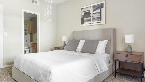 1 dormitorio blanco con 1 cama grande y espejo en Landing Modern Apartment with Amazing Amenities (ID8382X95), en Tulsa
