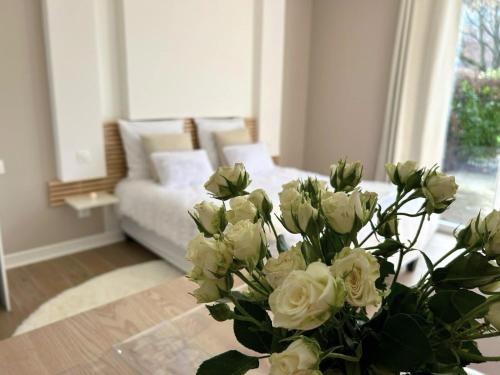 a vase of white roses on a table in a living room at Les Fontaines d'O in Castelnau-dʼEstrétefonds