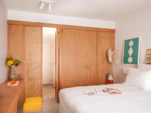 sypialnia z białym łóżkiem i drewnianym zagłówkiem w obiekcie Vertime Les Sables w mieście Les Sables-dʼOlonne