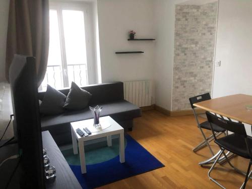 a living room with a black couch and a table at Belle Paris in Le Raincy