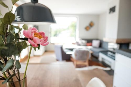 a vase with a pink flower on a table in a living room at Suite Franz Tegernsee in Tegernsee