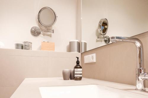 a bathroom sink with a bottle of soap on it at Suite Franz Tegernsee in Tegernsee