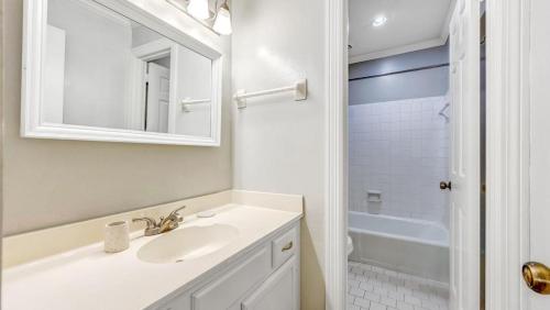 ein weißes Badezimmer mit einem Waschbecken und einem Spiegel in der Unterkunft Landing Modern Apartment with Amazing Amenities (ID9248) in Nashville