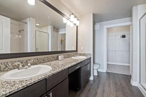 uma casa de banho com 2 lavatórios e um espelho grande em Landing Modern Apartment with Amazing Amenities (ID3876) em Carrollton