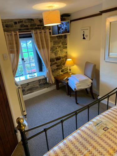 Schlafzimmer mit einem Bett, einem Schreibtisch und einem Fenster in der Unterkunft Superbly appointed 300 year old stone cottage in Bakewell